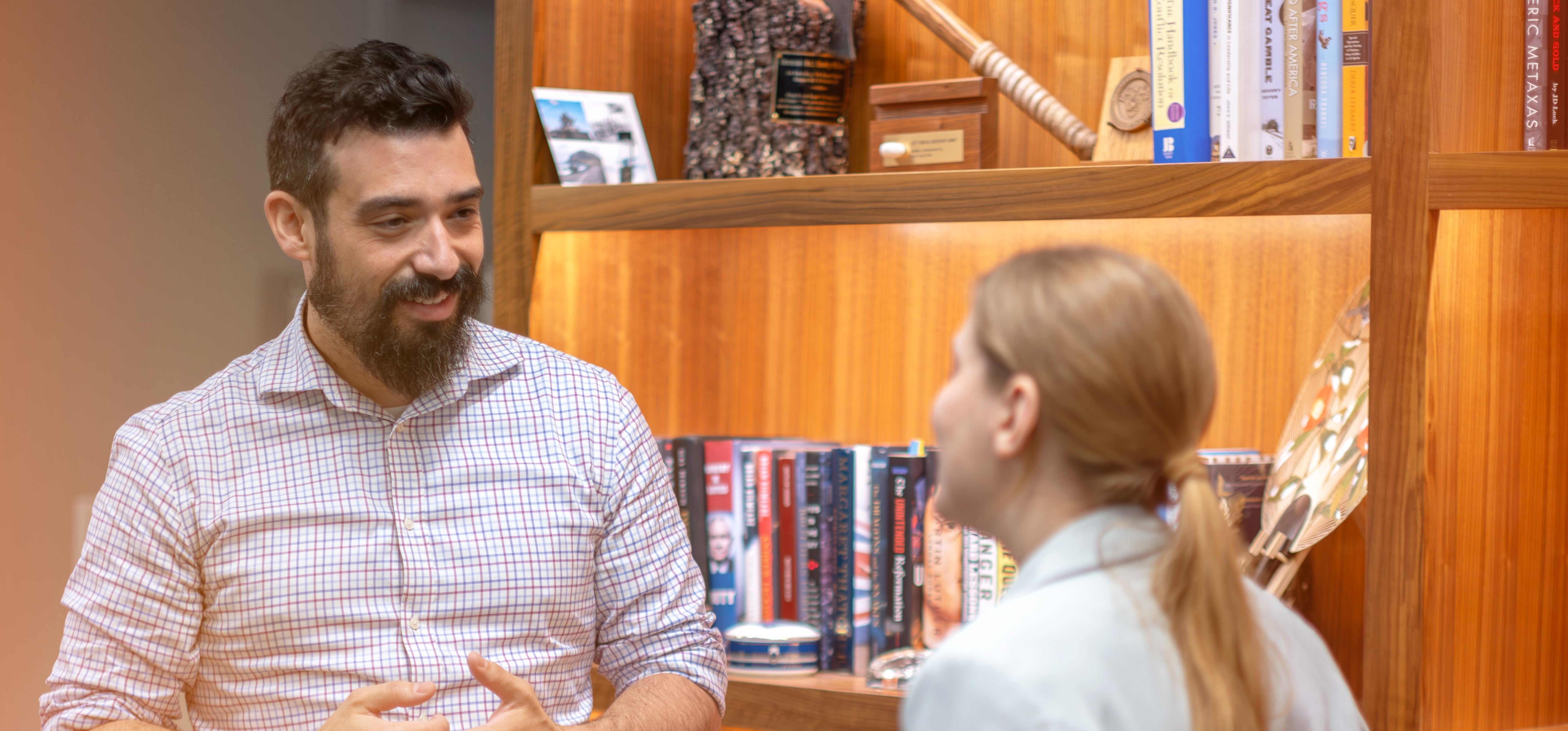 Two Employees in Conversation Near a Bookshelf